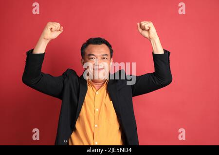 The Asian middle aged man standing on the red background. Stock Photo