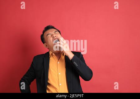 The Asian middle aged man standing on the red background. Stock Photo