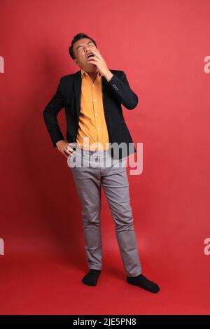 The Asian middle aged man standing on the red background. Stock Photo