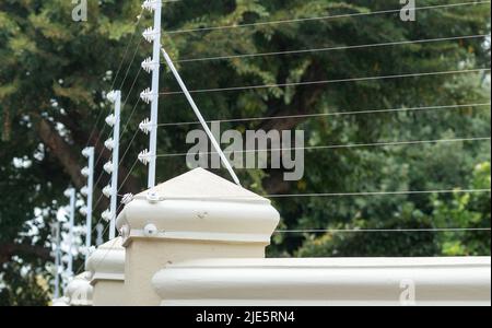 electric wires, electric fence closeup on a perimeter wall concept technology in safety and security in South Africa Stock Photo