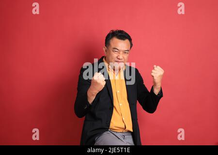 The Asian middle aged man standing on the red background. Stock Photo
