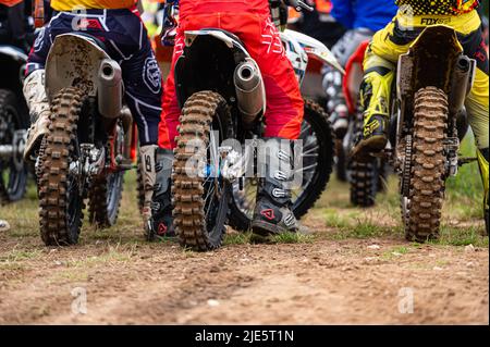 Dobele, Latvia, June 18, 2022: a group of motocross riders getting ready for the start, rear view, motocross sport Stock Photo
