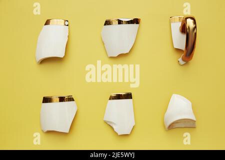 Creative aesthetic broken cup's pieces on yellow background. Creative conceptual home decorations idea. Hope, cozy home concept Stock Photo