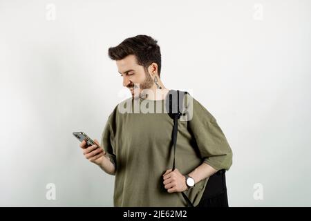 Cheerful caucasian man wearing casual clothes posing isolated over white background reading message on smart phone. Stock Photo