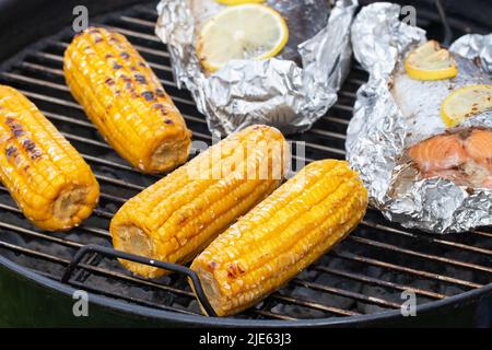 Several ears of corn are roasted on a round grill. Stock Photo