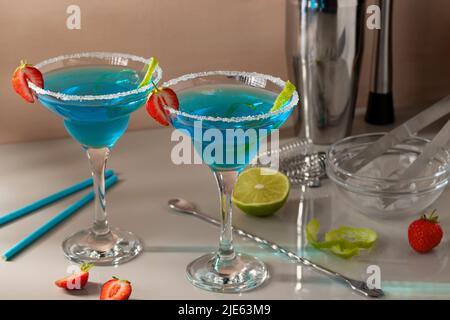 Fresh homemade blue margarita cocktail garnished with lime zest and strawberries, selective focus. Stock Photo