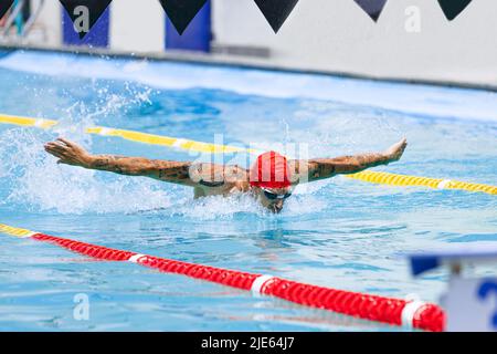 Young muscular man, professional swimmer in goggles training at public swimming-pool, outdoors. Sport, power, energy, style, hobby concept. Stock Photo