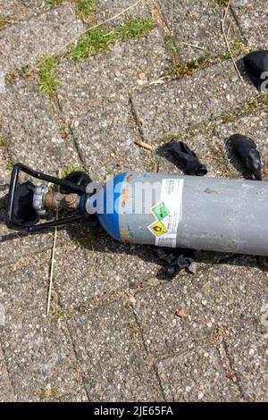 Cylinders with nitrous oxide and black balloons left in parking lot after use as drugs in The Hague Stock Photo