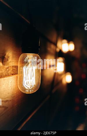 Incandescent Edison type bulb on wooden wall. Stock Photo