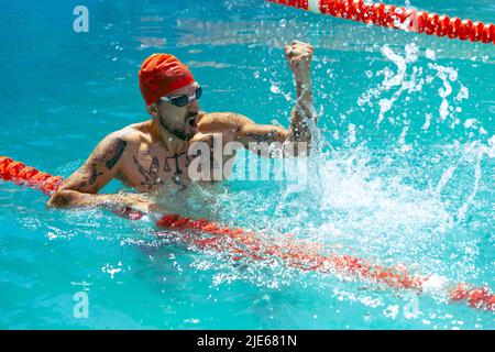 Win. Live portrait of young sportive man, professional swimmer in goggles training at public swimming-pool, outdoors. Sport, power, energy, style Stock Photo