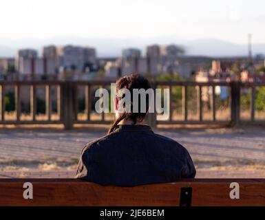 Alone pensive man looking at the sunset in the city sitting on a bench Stock Photo