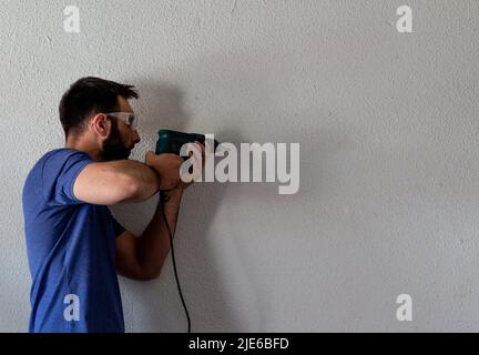short-haired dark-haired man with blue t-shirt works on construction Stock Photo