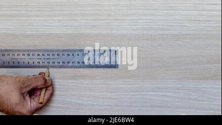Working with the hands. Carpenter measuring a piece of furniture with a metal Stock Photo
