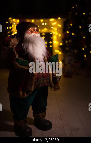 Santa Claus carrying big bag full of gifts, at home near Christmas Tree Stock Photo