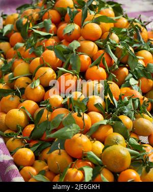 freshly picked oranges with leaves on on a market stall Stock Photo