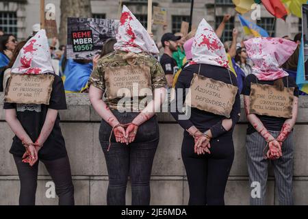 London, UK. 25th June 2022. Ukrainians and supporters stage a bloody protest demanding all prisoners of war, currently held by Russian forces, be immediately released. Russia continues to advance and deploy aggressive military action on multiple regions of Ukraine including Kyiv. Credit: Guy Corbishley/Alamy Live News Stock Photo