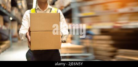 Close-up, workers carrying boxes in a large logistics warehouse. Concept of export-import logistics system. parcel box at warehouse, packaging, delive Stock Photo