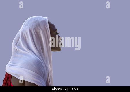 African Ghana woman standing with a white shawl covering her hair Stock Photo