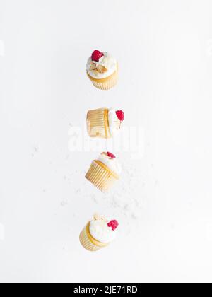 Small cupcakes with cream and raspberries in frozen flight on a white background. Minimalism. Light summer dessert. Restaurant, hotel, cafe, confectio Stock Photo