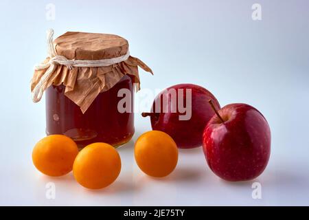 Fruit jam in a glass jar surrounded by ingredients, apples and plums. Harvest day Stock Photo