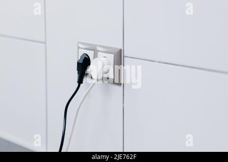 White and black cables in a socket on a white wall. High quality photo Stock Photo