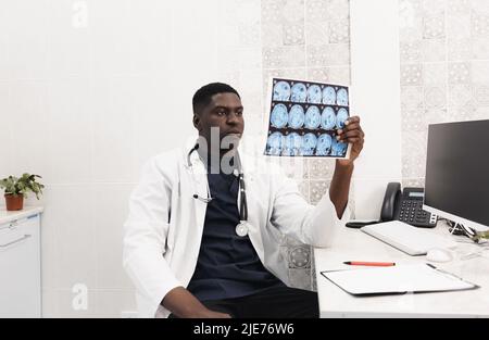 Close-up of an African-American doctor in a white coat looking at an X-ray image, CT, MRI,. Department of Radiology Stock Photo