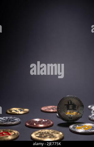 One Silver BTC Bitcoin close up, centered with other bitcoins coins lied on the desk on a dark background. Stock Photo