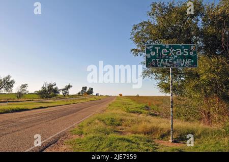 A sign covered in stickers marking the Texas state line stands alongside historic Route 66 outside the small Oklahoma town of Texola. Stock Photo