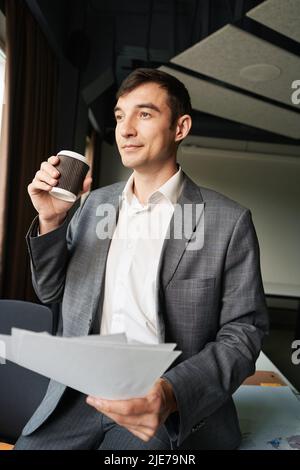 Male drinking coffee at his workplace while keeping papers Stock Photo