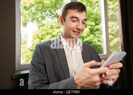 Man in suit texting message on smartphone at workplace Stock Photo