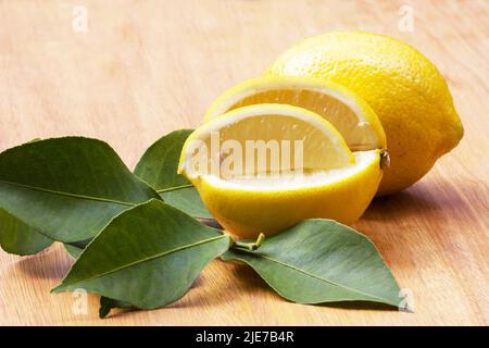 Fresh lemons and leaves on wooden background Stock Photo