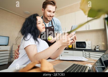 Female and joyous male reading good news on smartphone Stock Photo
