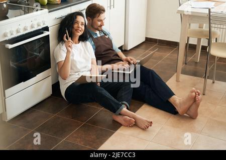 Woman sitting beside man on kitchen floor Stock Photo