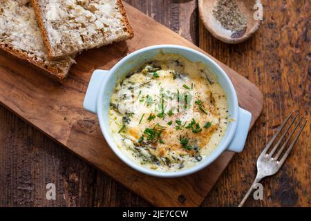 Egg baked in spinach and bechamel sauce Stock Photo