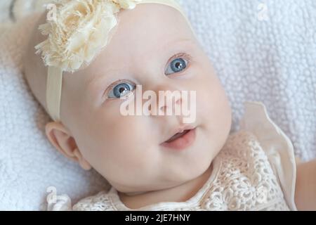 Portrait of a beautiful little baby girl with blue eyes lying on her back. happy family concept Stock Photo