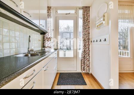 Interior of bright kitchen with balcony doors in modern apartment at daytime Stock Photo