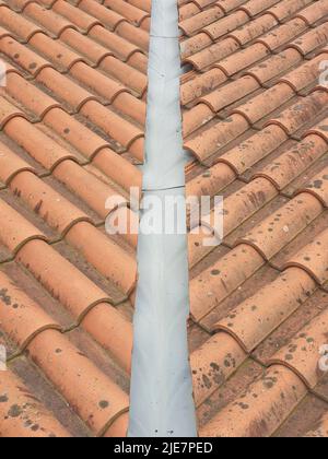 Closeup of red clay roof tiles with downspout in the middle of the roof Stock Photo