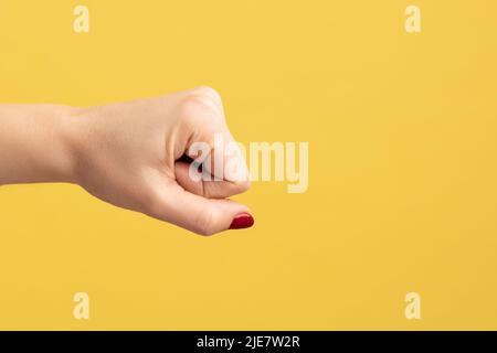 Profile side view closeup of woman hand showing boxing fists with hand, attack or defense against problems. Indoor studio shot isolated on yellow background. Stock Photo