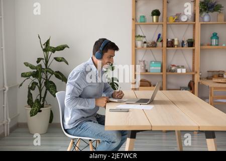 Man in headphones using laptop, listen audio course, making task Stock Photo