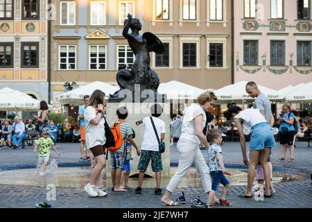 Warsaw, Poland. 25th June, 2022. People walk by the monument of the Mermaid of Warsaw, the symbol of the Polish capital is seen in the centre of Warsaw's Old Town. Daily life summer evening in Warsaw Old town after a hot Saturday. Credit: SOPA Images Limited/Alamy Live News Stock Photo