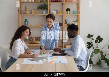 Three multiracial teammates work together on sales stats analysis Stock Photo