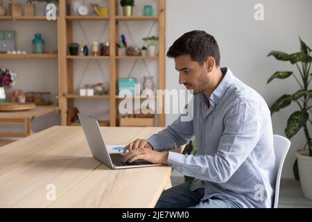 Hispanic businessman working on laptop seated at modern cozy workplace Stock Photo