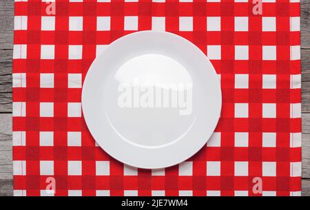Porcelain plate on a red checkered napkin. View from above Stock Photo
