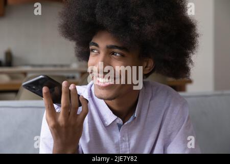 African guy holds smartphone make call speaking on speaker phone Stock Photo