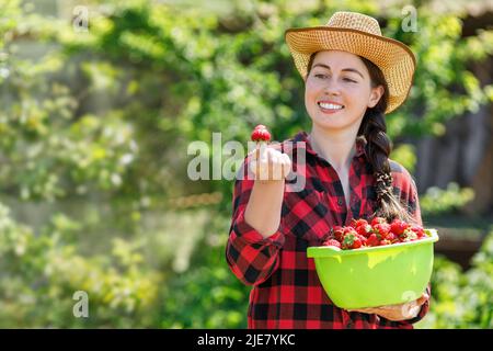 happy young woman farmer with strawberries in bowl outdoors Stock Photo