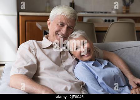 Beautiful mature spouses relaxing on couch staring at camera Stock Photo
