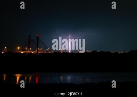 Branched lightning bolt strikes behind a cable-stayed bridge over river Waal at night Stock Photo
