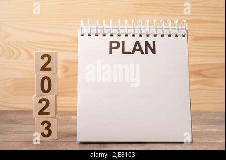 Mockup 2023 notepad with PLAN text. Text 2023 on wooden cubes. space for your text on notepad. 2023 Resolution Goals, Plan, Action text message on not Stock Photo
