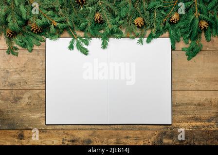 Christmas rustic mockup. sheet of white paper lies on an old table decorated with Christmas fir branches on old wooden table. christmas mock up Stock Photo