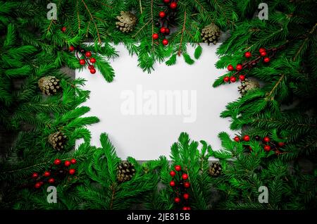 Christmas frame made of dark fir branches, cones, red berries and decorations. Christmas composition with frame of fir branches and pine cones. Merry Stock Photo